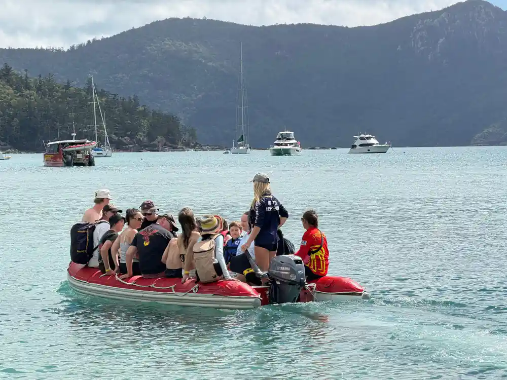 Group of tourists in red inflatable boat on turquoise water