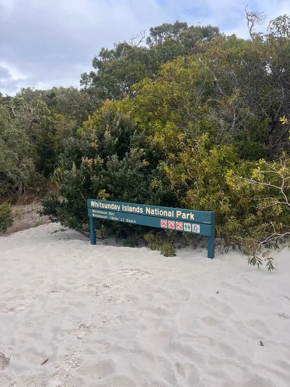 National park sign on sandy beach with vegetation