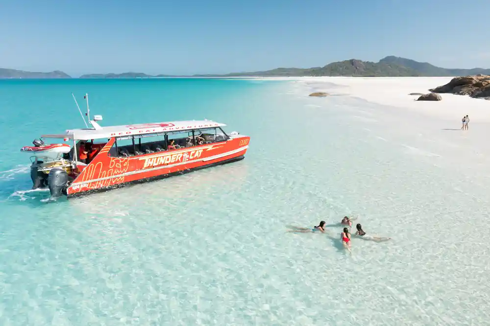 Orange speedboat anchored in shallow turquoise bay
