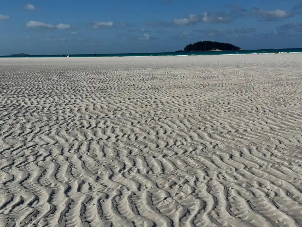 Sandy beach with ripple patterns and distant island