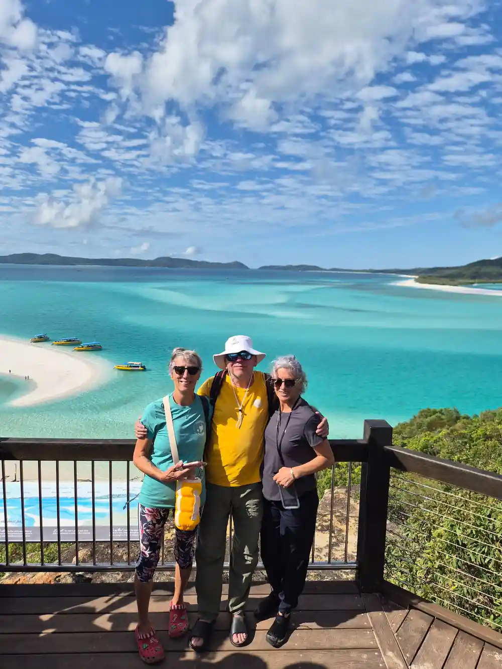 Three people on viewing platform overlooking turquoise bay