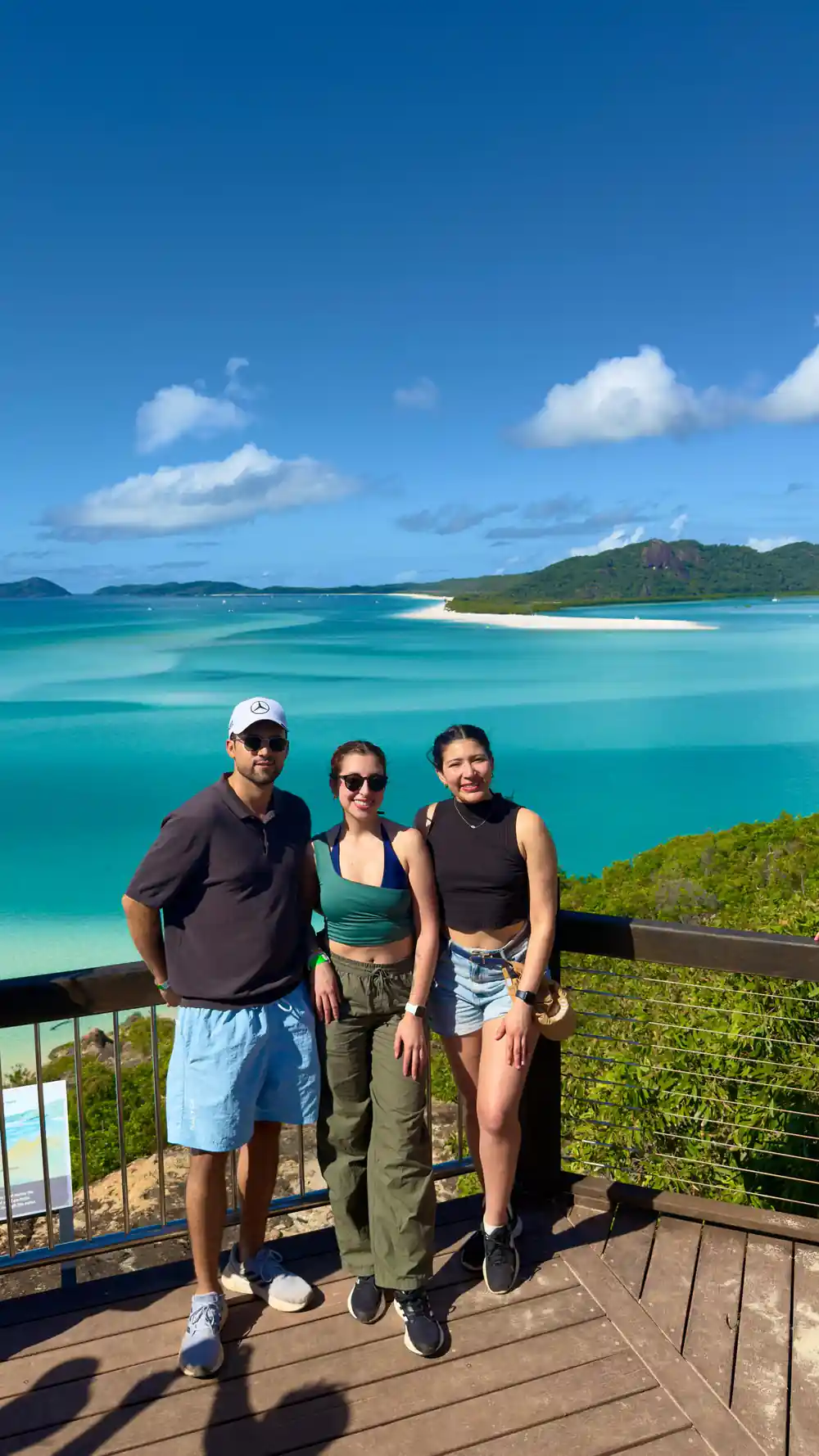Three people on wooden deck overlooking turquoise lagoon