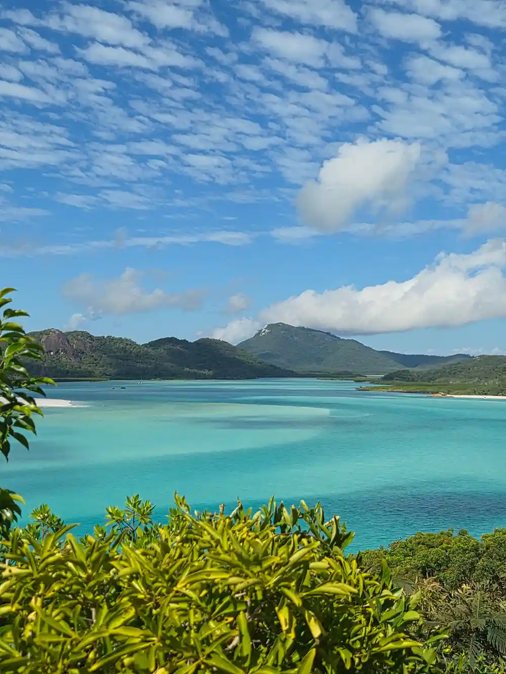Turquoise lagoon surrounded by forested hills and mountains