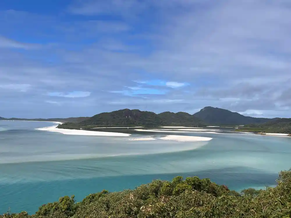 Turquoise lagoon with white sand and green hills