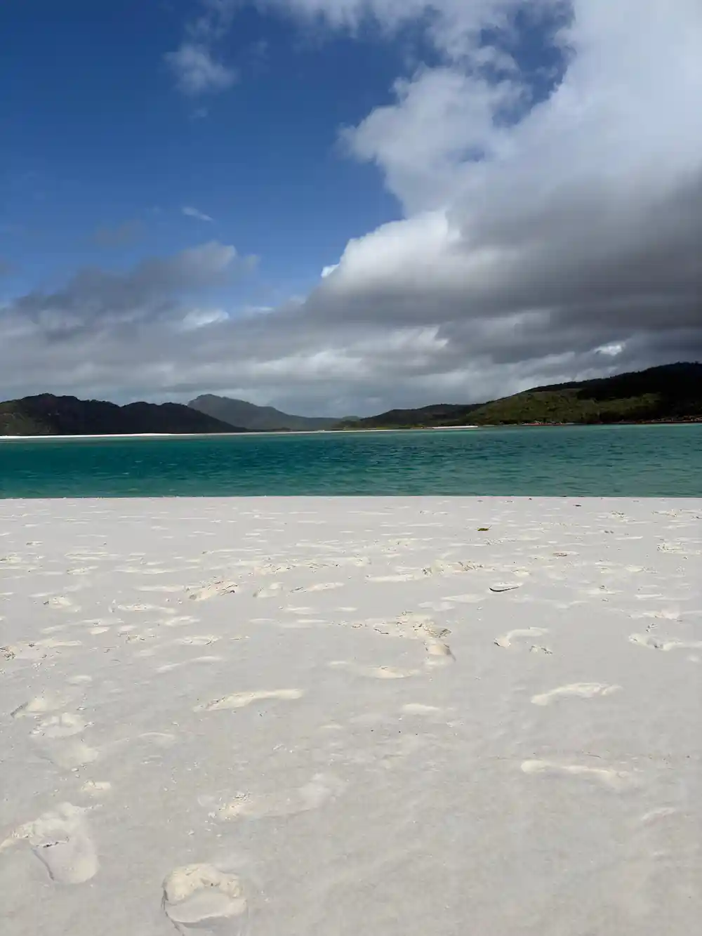White sand beach with turquoise water and distant mountains