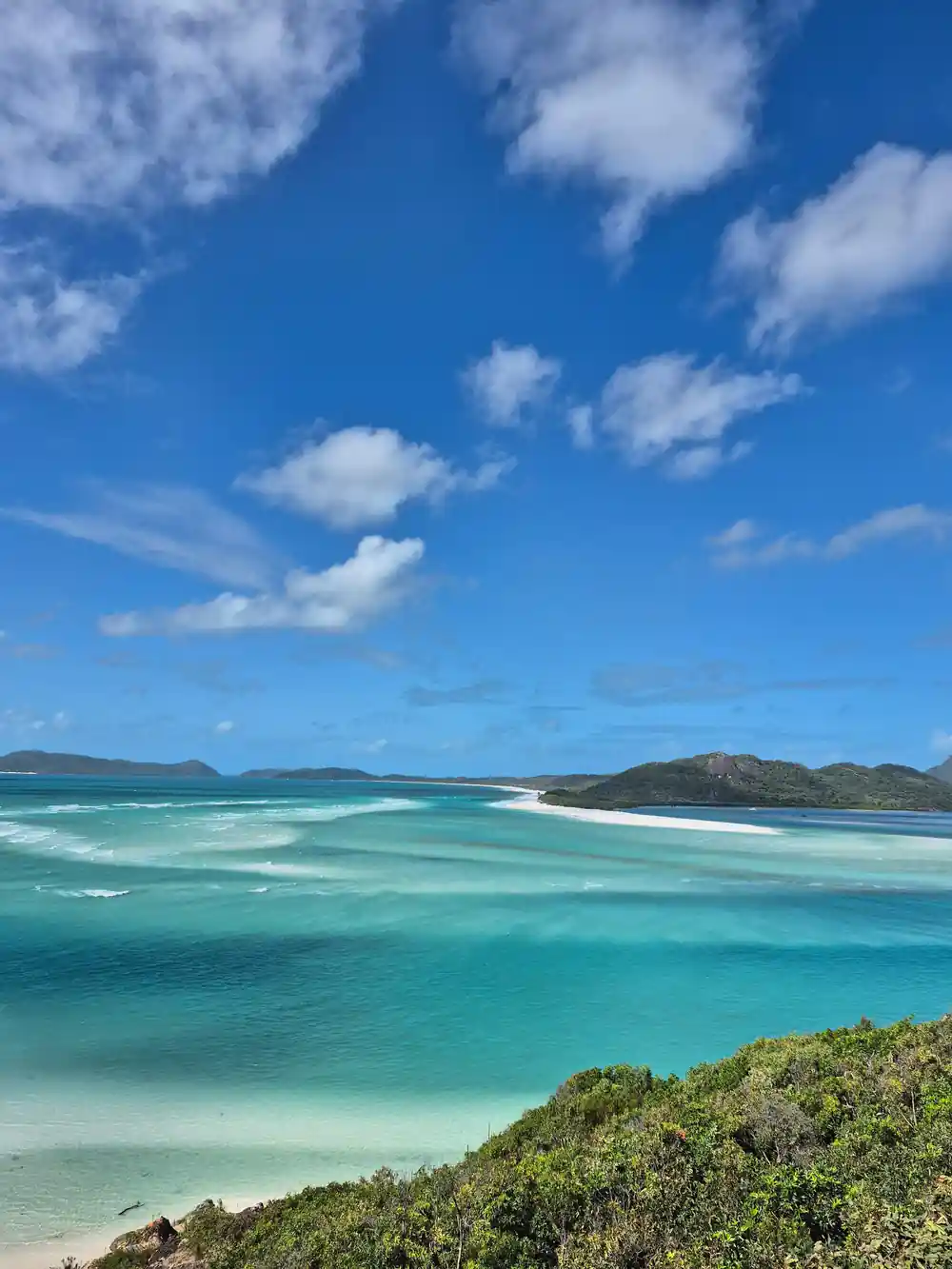 White sandy beach on island with blue water and distant islands