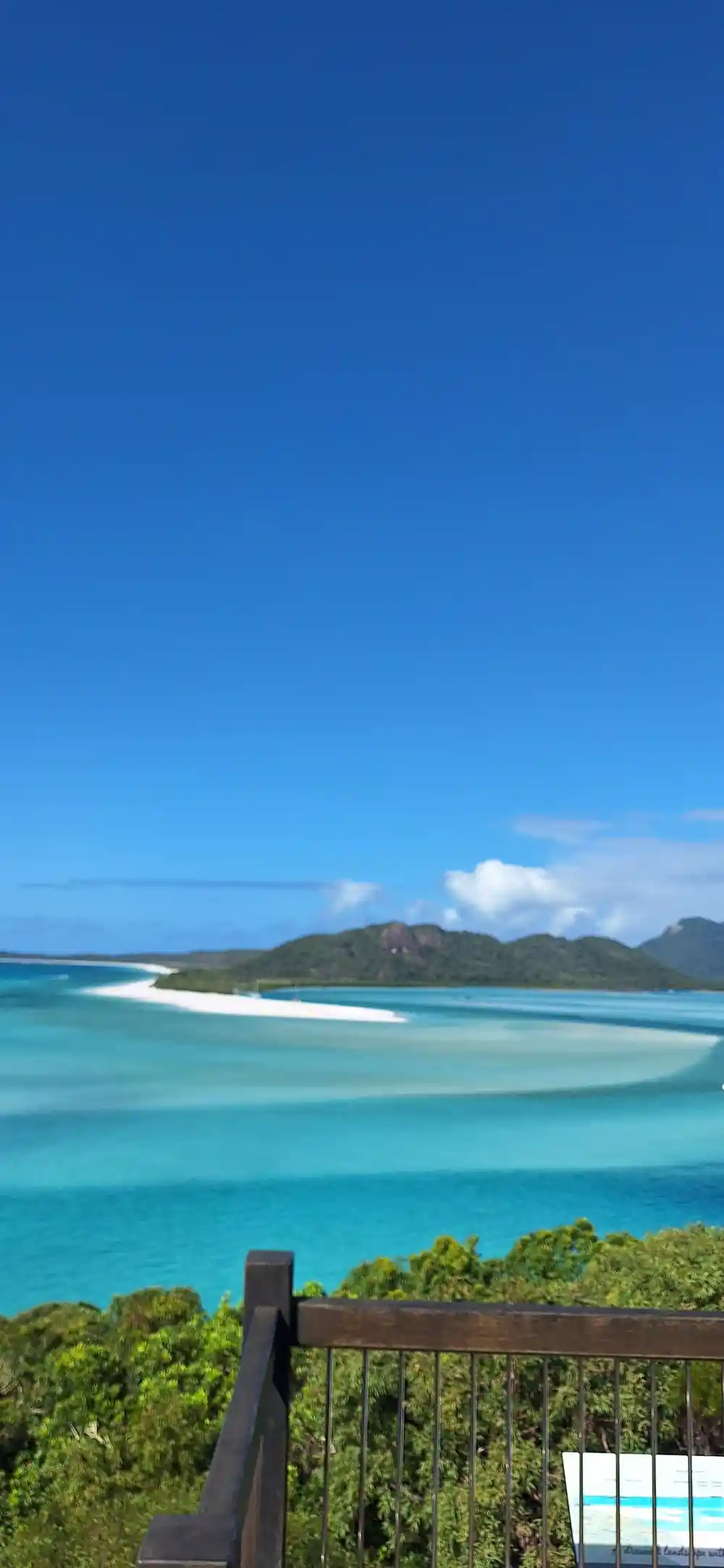 Wooden railing overlooking white sand beach and lagoon